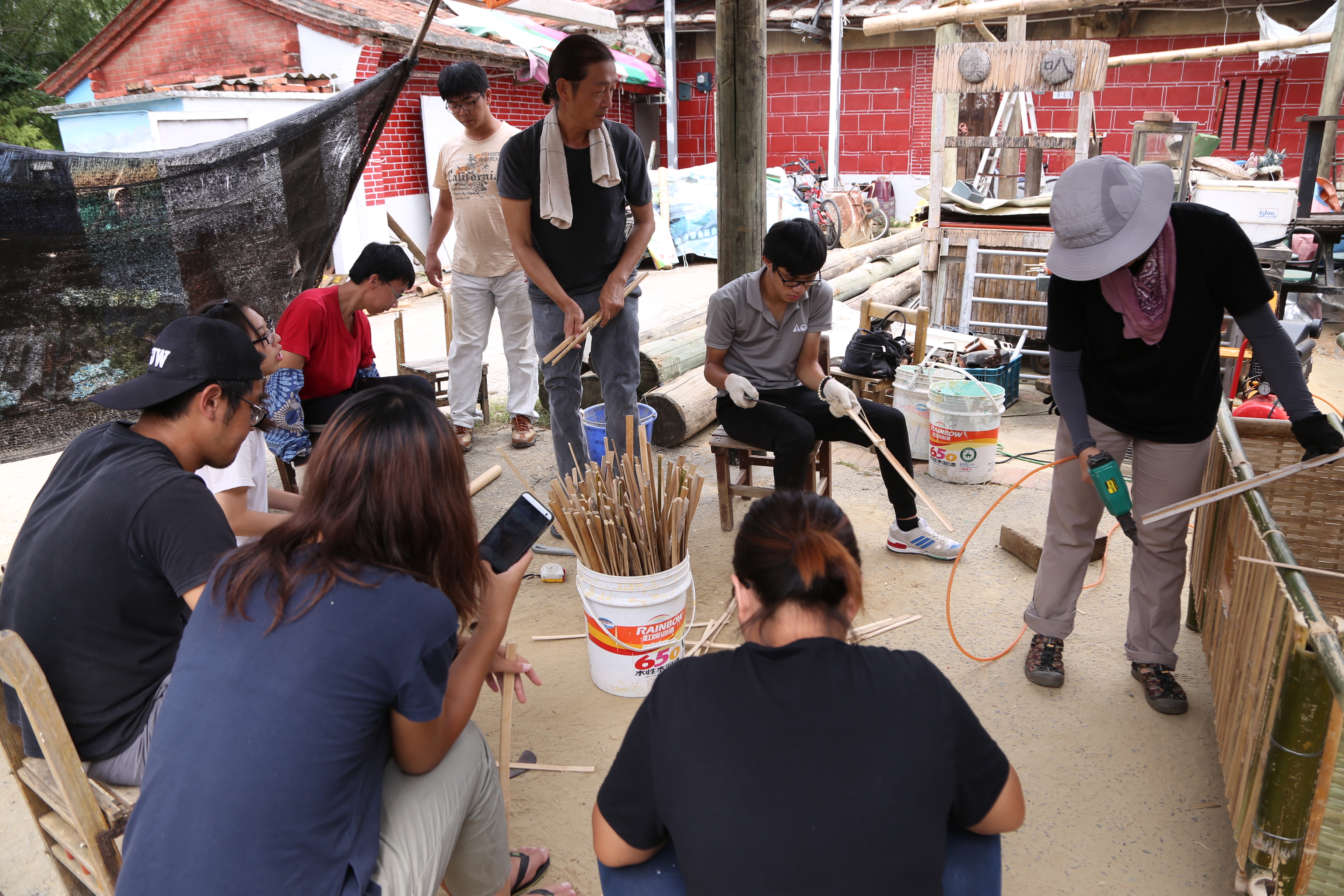 新光社區竹藝師傅教導打工換宿的青年砍竹、編竹等工藝製作