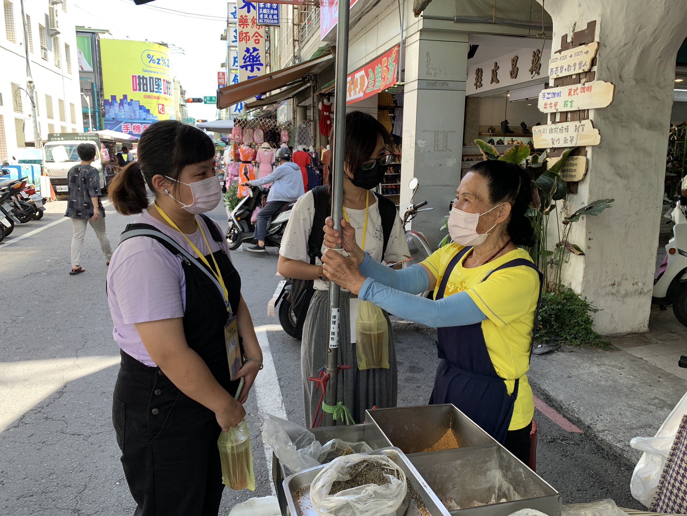 青年志工於屏東中央市場內和老店家採訪互動。