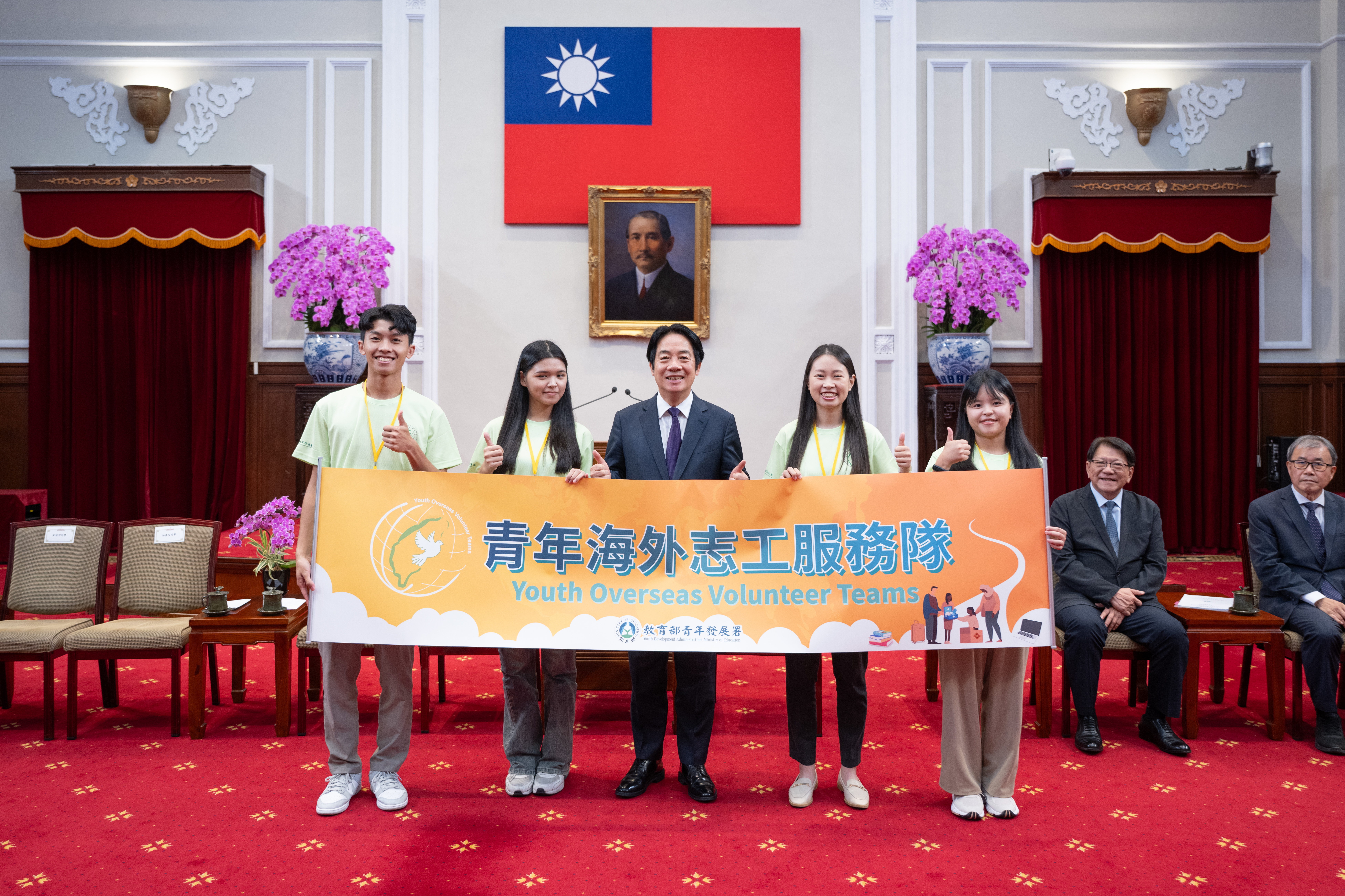 賴總統和四位青年志工代表授旗後合影，由左至右為紀冠宇、吳閩卉、李盈萱和林喬安。